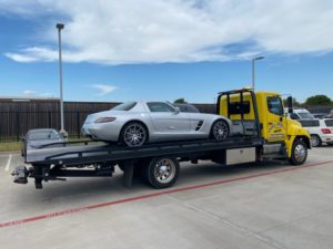 Yellow Flatbed Towing Truck Loaded with A Silver Sports Car