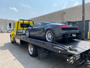 Yellow Flatbed Towing Truck Loaded With Gray Sports Car