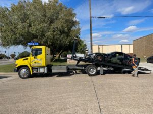 Yellow Flatbed Towing Truck Loading Black Camo Sports Car