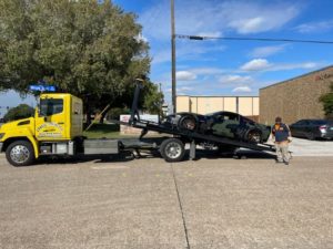 Flatbed Towing Truck Loading A Black Camo Sports Car