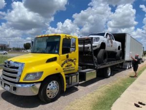 Flatbed Towing Truck Loading White Hilux Car To A Big Container Truck