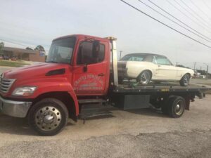 Red Chavez Towing Truck Loaded with White Old Vintage Car