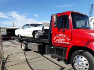 Red Chavez Towing Truck Loaded with White Vintage Car