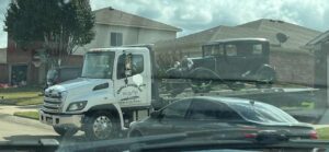 White Chavez Towing Truck Loaded With Black Vintage Car