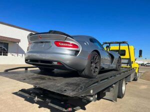 Yellow Chavez Towing Truck Loaded With Gray Luxury Car