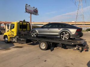 Yellow Chavez Towing Truck Loaded with Gray Sedan