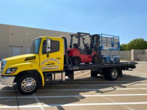 Yellow Towing Truck Loaded with Red Forklift