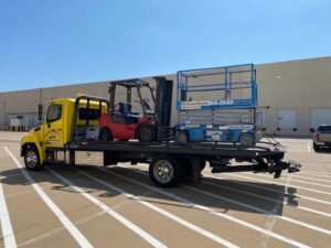 Yellow Towing Truck Loaded With Small Red Forklift